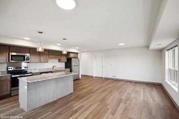 an empty living room with a kitchen with a counter top